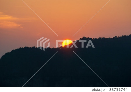 Sunrise behind the mountains, the shadows of the mountains, the orange sky with faint clouds. Sunrise behind the mountains, the shadows of the mountains, the orange sky with faint clouds. 88751744
