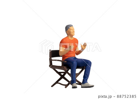 Miniature people sitting on chair isolated on white background Miniature people sitting on chair isolated on white background 88752385
