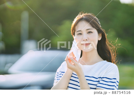 屋外でマスクを外す笑顔の若い女性 88754516