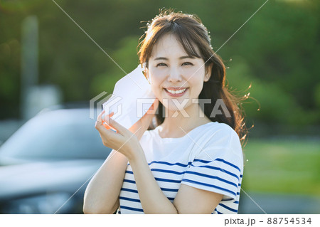 屋外でマスクを外す笑顔の若い女性 88754534