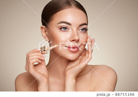 Portrait beautiful young woman with clean fresh skin. Model with foundation makeup bottle. Cosmetology, beauty and spa Portrait beautiful young woman with clean fresh skin. Model with foundation makeup bottle. Cosmetology, beauty and spa 88755166