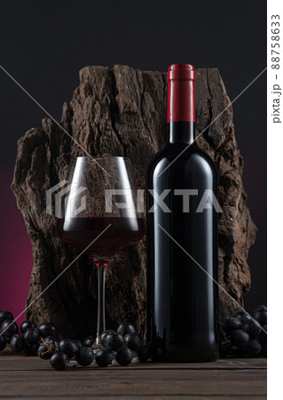Bottle, glass of Spanish red wine and grapes on  wooden base on black and red background. 88758633
