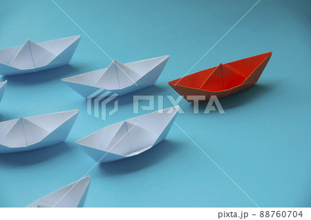 Leadership Concept - Orange color paper ship origami leading the rest of the white paper ship on blue cover background. Copy space concept 88760704