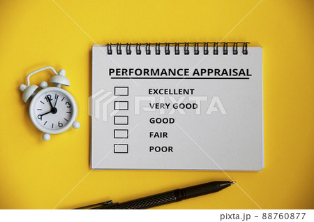 Performance appraisal checklist on notepad with pen and alarm clock on yellow cover background. Performance review concept 88760877