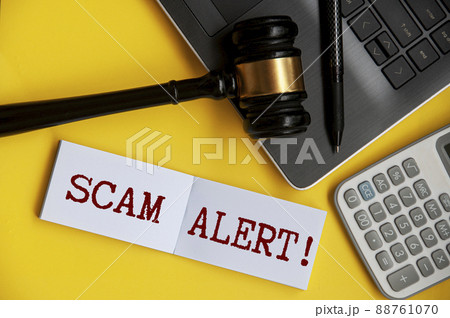 Scam alert text on notepad with gavel, laptop, pen and calculator background. Security concept 88761070