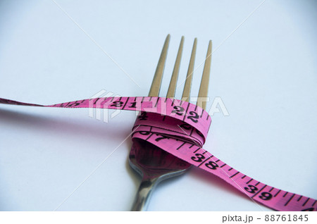 Fork tied up with measuring tape. Weight loss concept Fork tied up with measuring tape. Weight loss concept 88761845