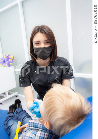 Dentist young woman examining the teeth of a little boy in a modern clinic Dentist young woman examining the teeth of a little boy in a modern clinic 88762010