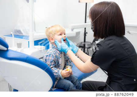 A cute little boy sits at the dentist, opened his mouth, showing his teeth to the dentist. Happy boy is sitting in the dentist's chair. Dentist - young brunette woman A cute little boy sits at the dentist, opened his mouth, showing his teeth to the dentist. Happy boy is sitting in the dentist's chair. Dentist - young brunette woman 88762049