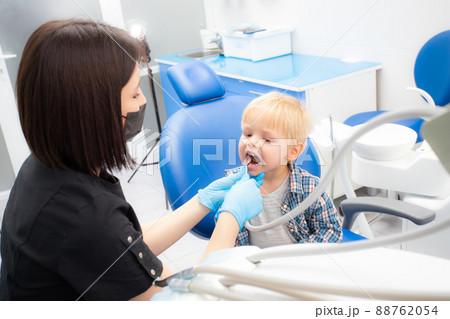 A cute little boy sits at the dentist, opened his mouth, showing his teeth to the dentist. Happy boy is sitting in the dentist's chair. Dentist - young brunette woman A cute little boy sits at the dentist, opened his mouth, showing his teeth to the dentist. Happy boy is sitting in the dentist's chair. Dentist - young brunette woman 88762054