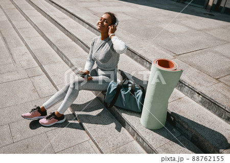Smiling woman looking happy while sitting outdoors after gym workout Smiling woman looking happy while sitting outdoors after gym workout 88762155