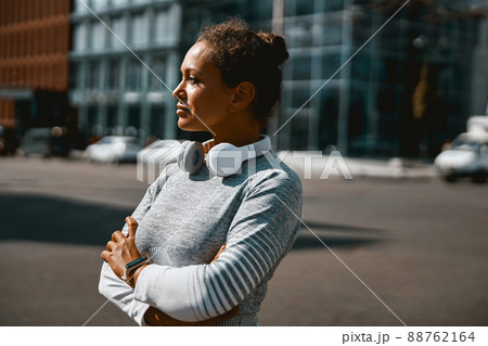 Thoughtful sporty woman looking away while standing outdoors in the daytime 88762164