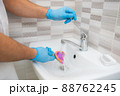 The dentist rinses the dental impression with water under pressure. Close-up of dentist's hands in blue gloves 88762245