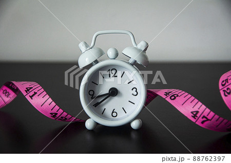 White alarm clock with measuring tape background. White alarm clock with measuring tape background. 88762397