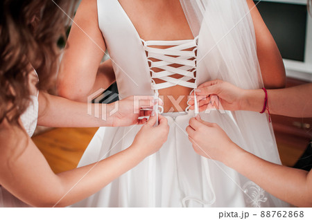 bridesmaids lace up the bride's dress 88762868
