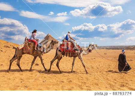 Tourists riding camels near the Pyramids of Giza Tourists riding camels near the Pyramids of Giza 88763774