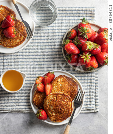 Breakfast of pancakes with strawberries and honey on a striped tablecloth. Top view Breakfast of pancakes with strawberries and honey on a striped tablecloth. Top view 88764811