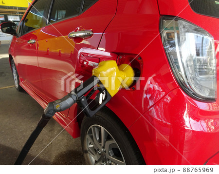 KUALA LUMPUR, MALAYSIA -FEBRUARY 3, 2018: Pumping fuel for red car using a yellow nozzle at the pump station. KUALA LUMPUR, MALAYSIA -FEBRUARY 3, 2018: Pumping fuel for red car using a yellow nozzle at the pump station. 88765969