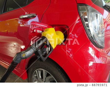 KUALA LUMPUR, MALAYSIA -FEBRUARY 3, 2018: Pumping fuel for red car using a yellow nozzle at the pump station. KUALA LUMPUR, MALAYSIA -FEBRUARY 3, 2018: Pumping fuel for red car using a yellow nozzle at the pump station. 88765971