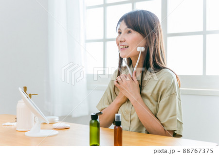 スキンケアする中高年女性(美顔ローラー・笑顔) スキンケアする中高年女性(美顔ローラー・笑顔) 88767375