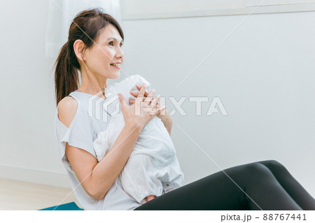 赤ちゃんを抱いてベビーヨガ・ベビービクスをする中高年女性 赤ちゃんを抱いてベビーヨガ・ベビービクスをする中高年女性 88767441