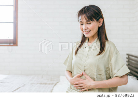 お腹を触るミドル世代の女性（笑顔） 88769922