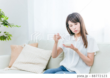 ソファでヨーグルトを食べる女性(困る) ソファでヨーグルトを食べる女性(困る) 88772123