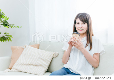 ソファでカップコーヒーを飲む中高年女性 ソファでカップコーヒーを飲む中高年女性 88772124