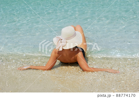 back view of young beautiful  woman with coconut relaxing at sunny tropical beach 88774170