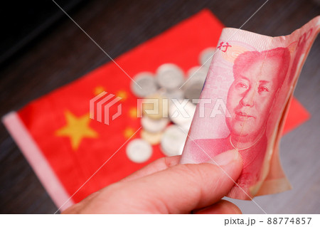 RMB banknotes of Chinese yuan money on the hand with a coins and China flag blurred on background RMB banknotes of Chinese yuan money on the hand with a coins and China flag blurred on background 88774857