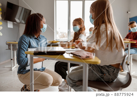 Young teacher talking to two schoolgirls in class 88775924