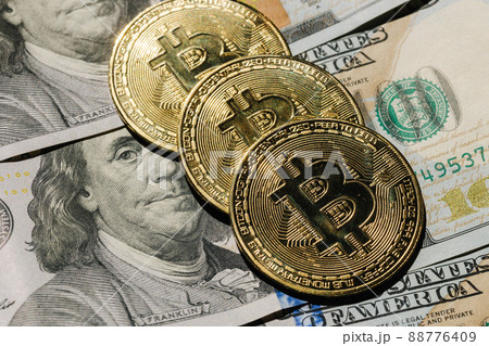 Close-up pf bitcoin on banknotes of one hundred dollars. Exchange US dollars for bitcoin. Cryptocurrency on dollar bills. Digital modern method of payment. Concep of virtual money. 88776409