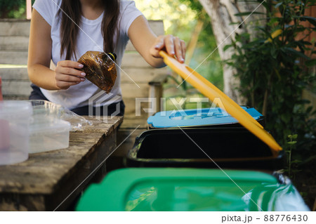 Woman open yellow bin for recycling and put plastic bottle inside. Close-up of female put rubbish in trash container. Recycling concept 88776430