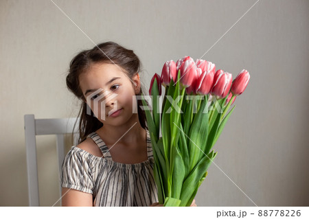 Portrait of a beautiful romantic little girl with a bouquet of pink tulips 88778226
