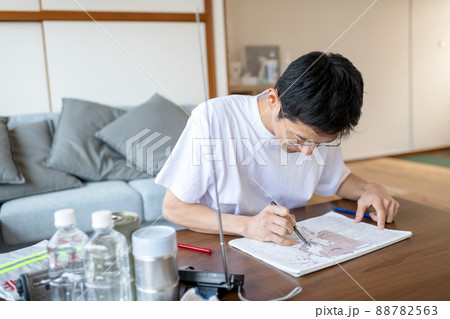 ラジオ放送聴きながら天気図を記入する防災訓練中の男性 88782563