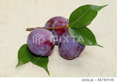 Sweet Purple Plum with green leaves on wooden table 88784546