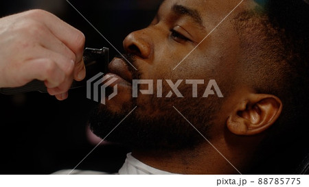 A white-skinned guy straightens the line of his mustache to a young African-American guy A white-skinned guy straightens the line of his mustache to a young African-American guy 88785775