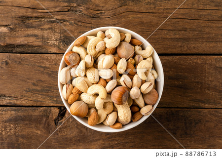 Mixed dried nuts (almonds, pistachios, peanuts, hazelnuts and cashews) in bowl on wooden table. Top view Mixed dried nuts (almonds, pistachios, peanuts, hazelnuts and cashews) in bowl on wooden table. Top view 88786713