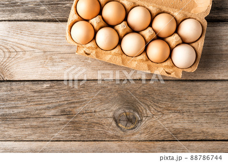 Overhead shot of chicken eggs in carton box on wooden table 88786744
