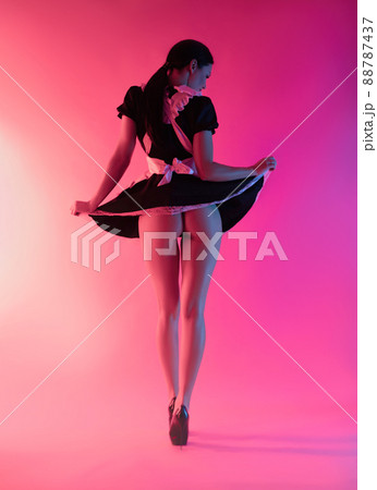 a sexy girl in a maid costume stands with her back exposing her buttocks in neon light 88787437