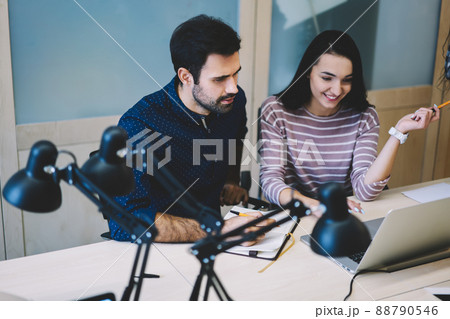 Satisfied coworkers working on laptop together in office Satisfied coworkers working on laptop together in office 88790546