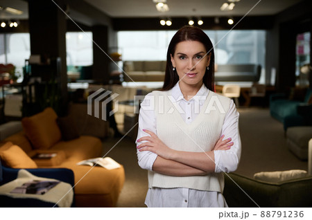 Confident female sales manager of a furniture store looking at camera smiling with arms crossed Confident female sales manager of a furniture store looking at camera smiling with arms crossed 88791236