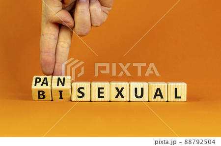 Pansexual or bisexual symbol. Doctor turns wooden cubes and changes the word 'bisexual' to 'pansexual'. Beautiful orange background, copy space. Social, pansexual or bisexual concept. 88792504