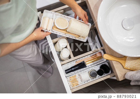 Top view of woman hands neatly organizing bathroom amenities and toiletries in drawer in bathroom. Top view of woman hands neatly organizing bathroom amenities and toiletries in drawer in bathroom. 88793021