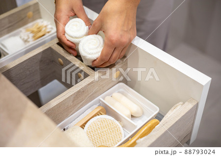 Top view of woman hands neatly organizing bathroom amenities and toiletries in drawer in bathroom. 88793024