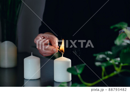 Close-up of the hands of a female beautician lighting scented candles in her small spa business. 88793482