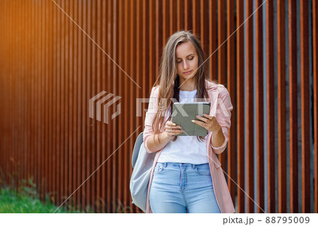 Woman using modern technology outside. Professional female manager reading information on tablet while walking outdoor. Woman using modern technology outside. Professional female manager reading information on tablet while walking outdoor. 88795009