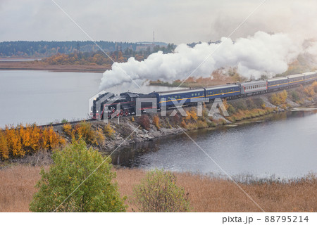 Retro steam train moves along the lake. Retro steam train moves along the lake. 88795214