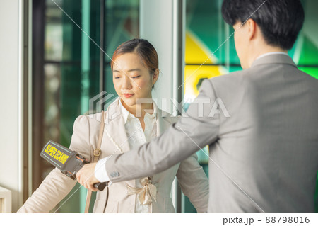 In the airport, people are going through the physical screening and luggage scanning procedures. 88798016