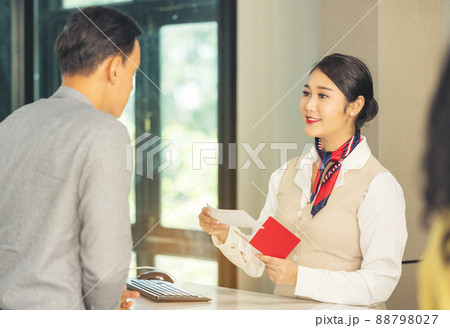 At the airport check-in counter, a passenger hands over his documents to the manager via a counter ticket. 88798027