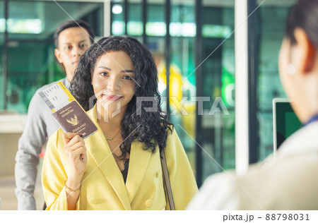 At the airport check-in counter, a passenger hands over his documents to the manager via a counter ticket. At the airport check-in counter, a passenger hands over his documents to the manager via a counter ticket. 88798031